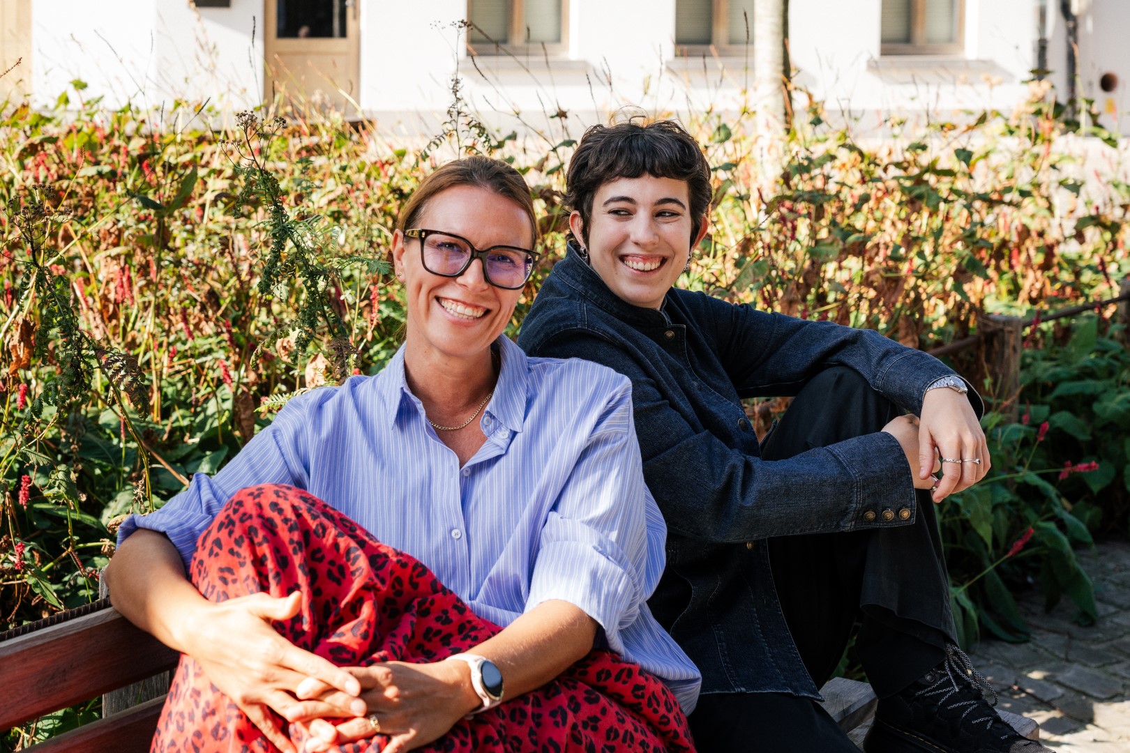 Two smiling women sitting together in a green garden in Ghent